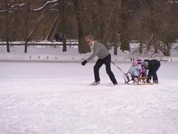 Englischer Garten, man on ice skates pull a sledge with his children, winter, snow Stock Footage