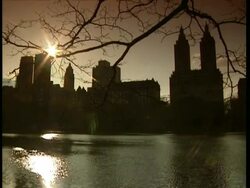MWA Sunlight shimmers on Central Park lake with skyscrapers silhouetted in background, New York Stock Footage