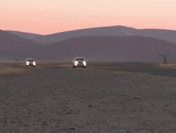 Vehicles driving through dunes, Sossusvlei, Namib-Naukluft, Namibia Stock Footage