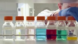 MS Scientist examining bottles of solution on shelf in research laboratory Stock Footage