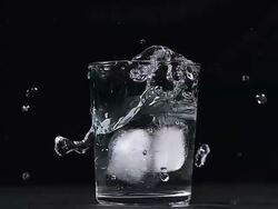 MS SLO MO Ice cubes falling into Glass of Water / Vieux Pont, Normandy, France Stock Footage