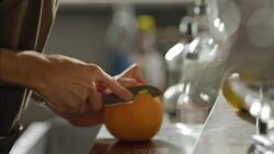 Bartender slices orange peel for specialty mixed drink Stock Footage