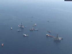 Aerial long shot of DeepWater Horizon oil spill recovery site, Discoverer Enterprise and rigs drilling relief wells for BP, oil spill patterns on water Stock Footage