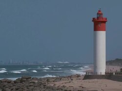 ES Lighthouse next to the shore with the Durban skyline in the distance / Durban, South Africa Stock Footage
