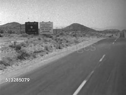 1952: NYE COUNTY, NEVADA: BASE CAMP MERCURY: WS (POV Front of slow moving vehicle) Sign 'US Atomic Energy Commission, Nevada Proving Ground, Camp Mercury', turning off main road. NTS, Nevada Test Site, restricted, testing, radioactive, Cold War. Instructional Video