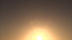 The sun shines brightly through clouds above rock formations in the Sahara Desert. Stock Footage