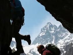 Boom shot as climbers scale vertical crack above mtns Stock Footage