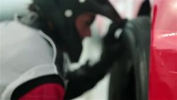 Pit-crew removes old race-car tire, replaces new tire, and tightens lug-nuts Stock Footage