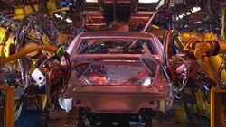Automotive robots weld a car on an assembly line as sparks fly. Stock Footage