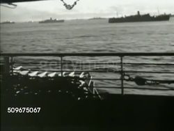 1942: U.S. NAVY  CONVOY TO NORTH AFRICA: (POV Moving ship) XWS U.S. Navy convoy at sea. LS Soldiers on transport ship deck, along railing. MS Soldiers sewing US flag patch onto uniform. WWII Instructional Video