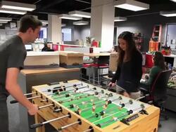 Woman and man play foosball in entrepreneurial office space Stock Footage