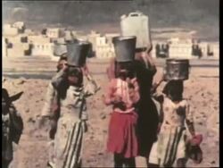 Third-world women from Africa and Asia carry water supplies on their heads and shoulders. News Clip
