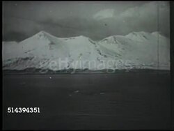 1942: ALEUTIAN ISLANDS: WS Waves washing up on beach w/ tall leaning tropical trees. MS PAN (R) Trees in dense forest. VS Aleutian Islands, mountains, hills. AERIAL: WS Dropping bombs over landscape. World War II, WWII, Alaska Instructional Video