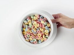 CU Woman hand entering setting down round white plate with bowl with colorful Fruit Loops breakfast cereal / Omaha, Nebraska, United States Stock Footage