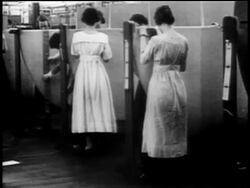 B/W 1917 REAR VIEW women sewing canvas on wings of warplanes in factory Stock Footage