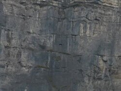 Wing suit flier descends from cliff, aiming for valley below Stock Footage