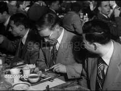 1951: HARVARD UNIVERSITY DORMS: PRE-CHRISTMAS DINNER: Unidentified House dining hall w/ male students in suits eating together at long tables, VS Students, Chef & helpers carrying something out on board, possibly The Boar's Head ceremony Kirkland. Instructional Video