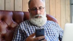 elderly professor is typing a message on a smartphone Stock Footage