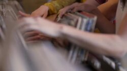 Young woman looks through vintage vinyl with friends in record store and finds treasure Stock Footage