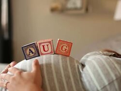 A pregnant women using blocks to spell the month of AUG on her stomach. Stock Footage