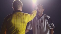 Medium shot OTS of referee; soccer player reacts to red card penalty Stock Footage