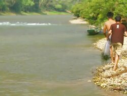 MS ZI SLO MO Shot of two men walking along river bank , holding fishing nets / Ou river, Luang Prabang, Laos Stock Footage