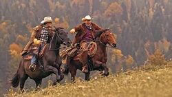SLO MO DS Two ranchers enjoying riding galloping horses uphill Stock Footage