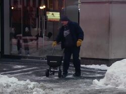 MS ZO ZI PAN Man spreading salt on side walk in business area / New York, New York, United States Stock Footage