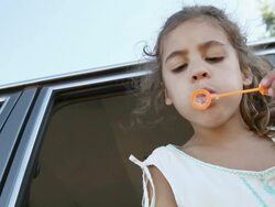 Girl blowing bubbles from car window, low angle view Stock Footage