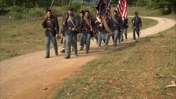 Union soldiers carry the Union flag as they march along a dirt road. Stock Footage