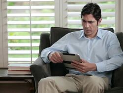 MS Man sitting on sofa and browsing on tablet computer / Portland, Oregon, United States Stock Footage