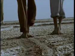 MCU low angle, Several pairs of feet treading salt into mud, Gujarat, India Stock Footage