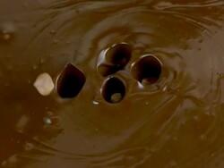 HD Super Slow-Mo: Hazelnuts Splashing Into Chocolate Stock Footage