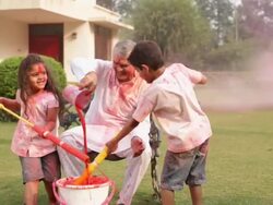 Senior man playing holi festival with his grandchildren in a lawn  Stock Footage