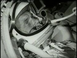 Astronaut John Glenn wears a spacesuit as he rides in a space capsule. News Clip