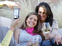 Hispanic friends drinking wine on patio and taking photographs Stock Footage