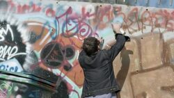Young man spraypaints name on graffiti wall Stock Footage