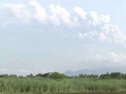 Merapi volcano erupts at dawn over rural landscape: falling ash threatens arable crops and farming. Indonesia. 7 November 2010 / AUDIO Stock Footage