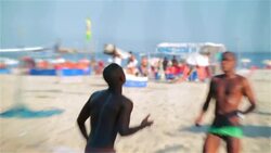 Athletic Brazilian players pass, set, and head soccer ball over net in beach footvolley match Stock Footage