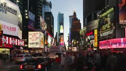 Traffic and pedestrians hurry below the flashing neon lights of Times Square. Stock Footage