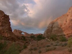 PAN Natural arch amongst rocky formations in desert landscape at Arches National Park / Utah, United States Stock Footage