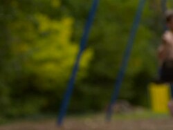 MS SLO MO shot of three Caucasian male children on park swings, nearest one lying on swing on his stomach / Stanford, Connecticut, United States Stock Footage