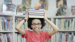 Male elementary student posing with books and an apple in library Stock Footage