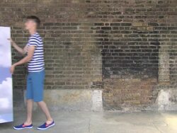 Young couple enter carrying a backdrop of sky and clouds, place backdrop by wall and walk off Stock Footage