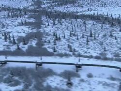 Extreme Long Shot aerial tracking-left zoom-out - The Alaska Pipeline stretches across the snowy Alaskan landscape. / Alaska, USA Stock Footage