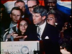 June 5 1968 zoom out Robert Kennedy making speech to crowd at rally / gives thumbs up + victory sign / low angle Stock Footage