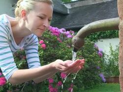 MS Young woman smiling and drinking water from well / Saarburg, Rhineland-Palatinate, Germany Stock Footage