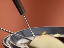 CU PAN apple slice on the end of fondue fork dipped into cheese fondue pot and coming out wrapped in melted cheese Stock Footage