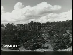 1949: ROYAL SWEDISH NAVY: WS Russian coastline across Baltic Sea. WS Finland coastline. HA MS Bow of Swedish battleship traveling down river. HA VS Sailors standing at attention on deck. WS Wake of ship. Patrol, Sweden. Instructional Video