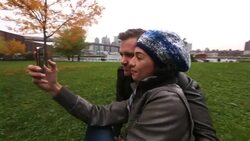Young woman takes smartphone photo with boyfriend, winks at the camera; New York skyline in background Stock Footage
